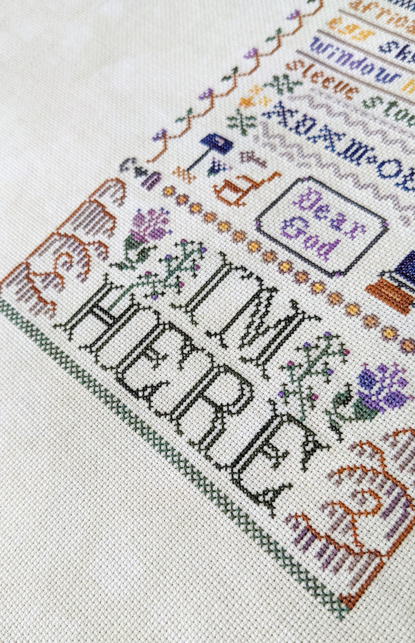 Cross-stitched text 'I'm Here' with decorative elements on a white background