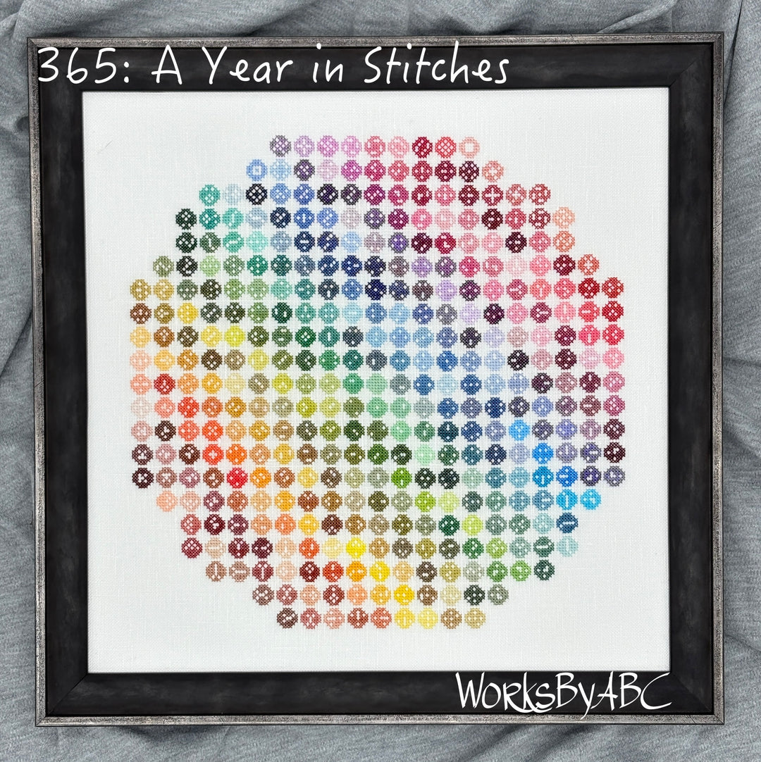 Framed cross-stitch art with colorful pattern on a white background, labeled '365: A Year in Stitches' by WorksByABC.