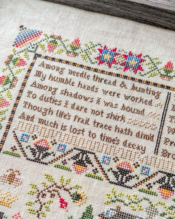 Cross-stitched text with decorative elements on a fabric background