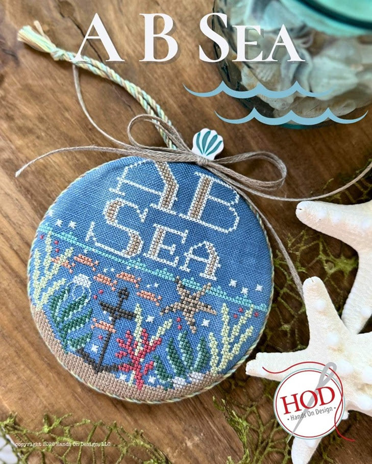 Decorative ornament with 'A B Sea' text and underwater design on a wooden surface.