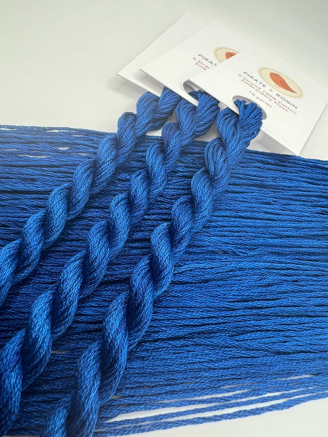 Blue yarn skeins on a white surface with a card in the background
