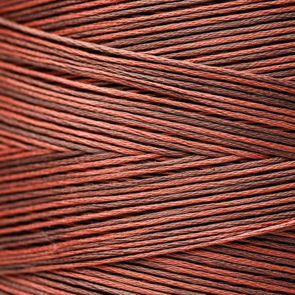 Close-up of tightly wound embroidery thread in a warm rust red and dark brown colorway, showing the texture and pattern of the yarn.