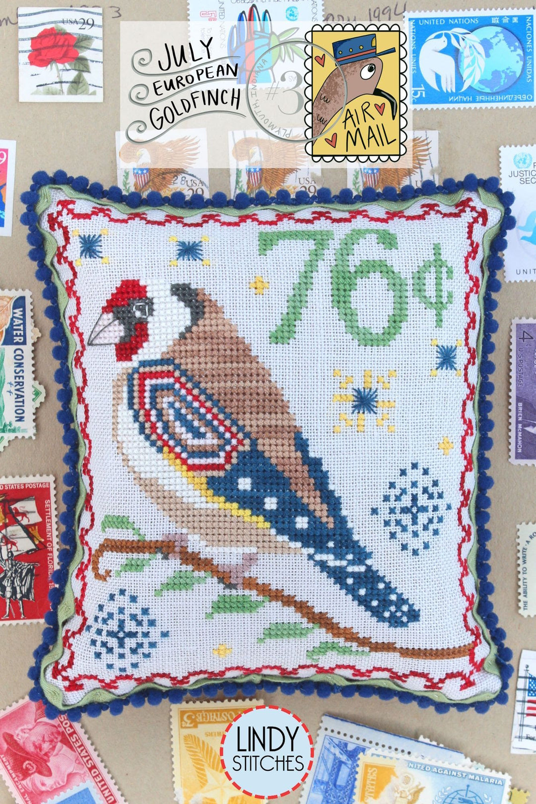 Cross-stitched pillow with a goldfinch design and postal-themed decorations on a background of stamps.