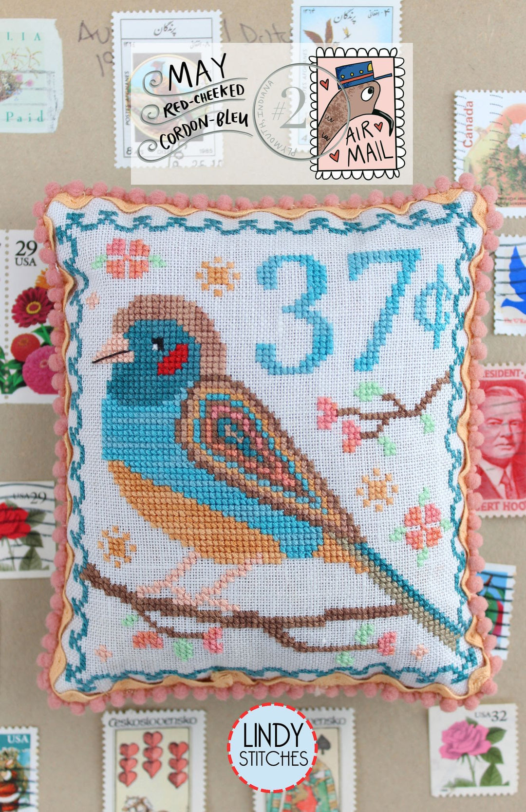 Cross-stitched pillow with a bird design and postal-themed decorations, featuring the Lindy Stitches brand.