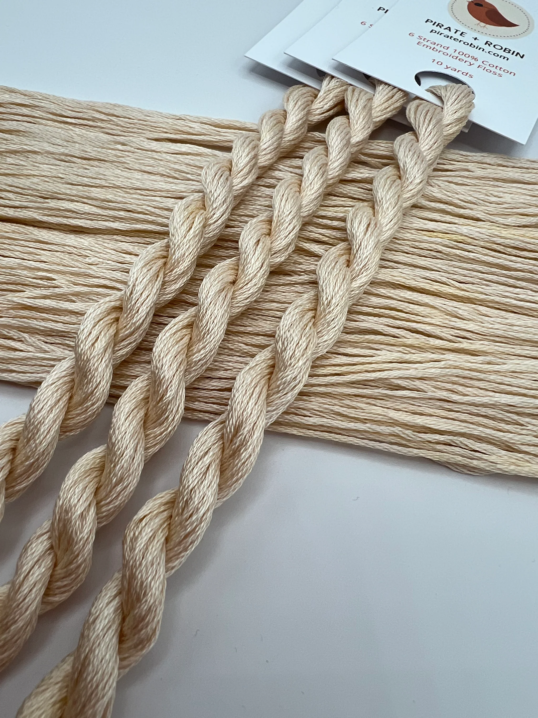 Beige embroidery floss with a brand label on a white background
