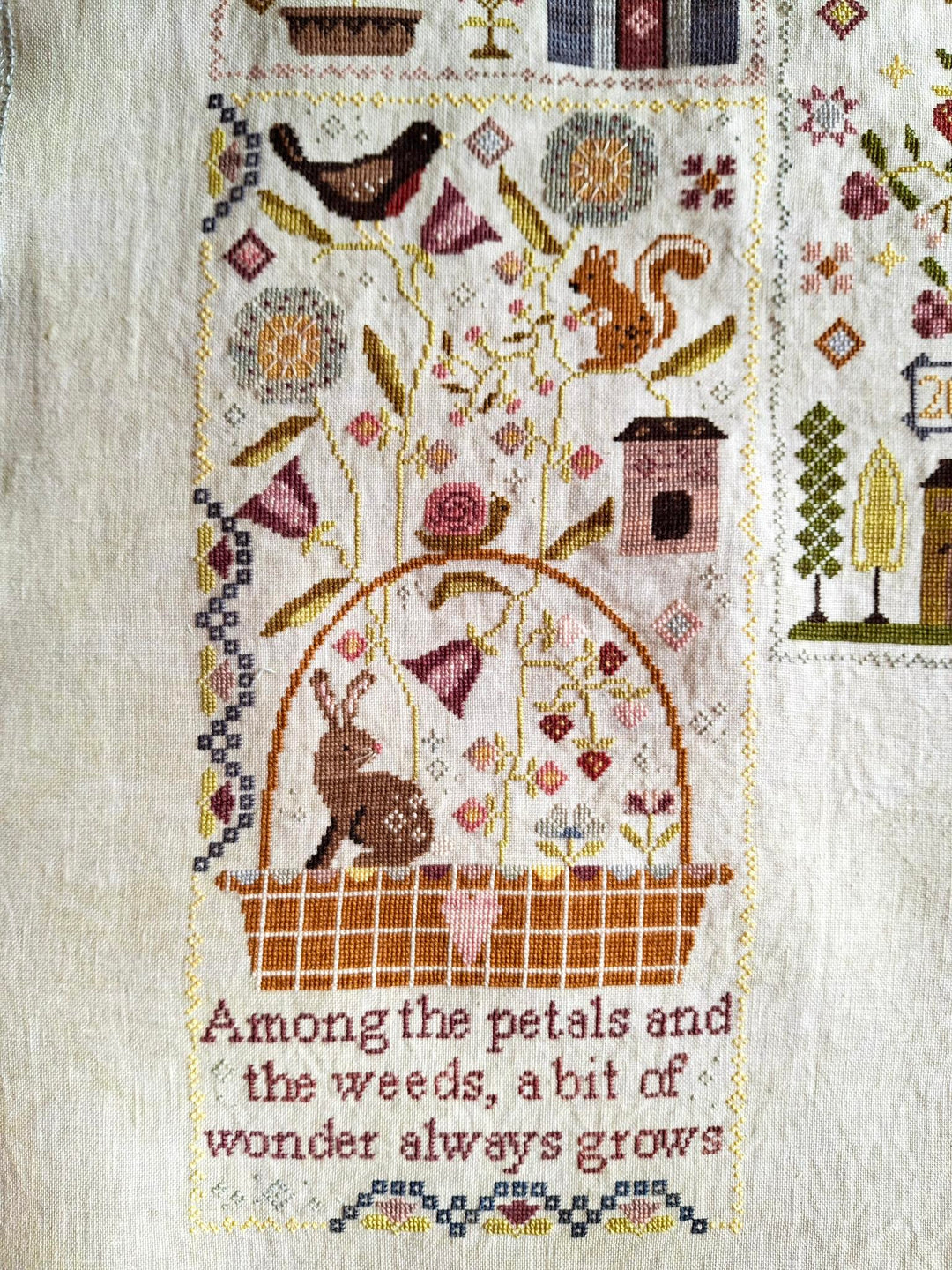 Cross-stitched design with animals and text on a textured fabric background