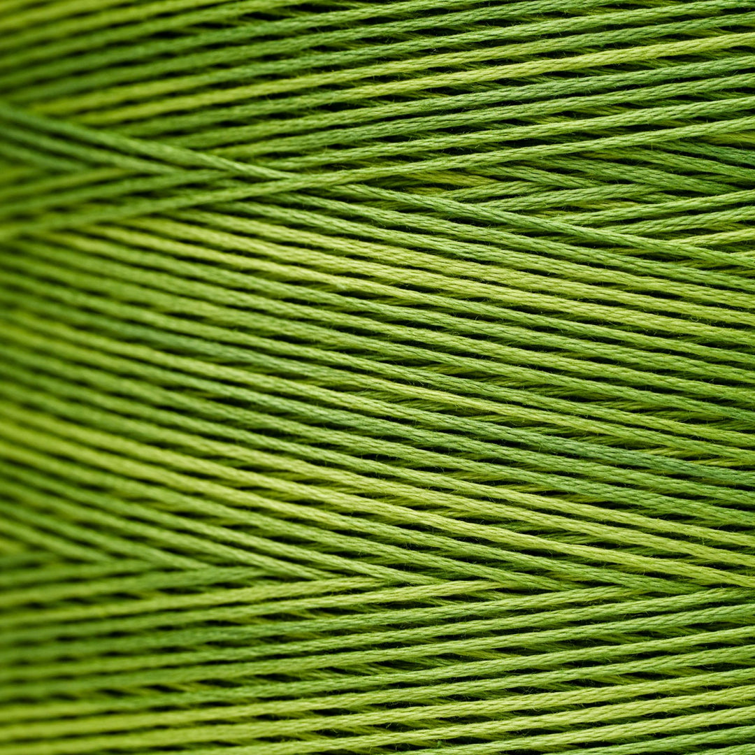 A close-up of bright olive green embroidery thread wound in parallel diagonal rows.