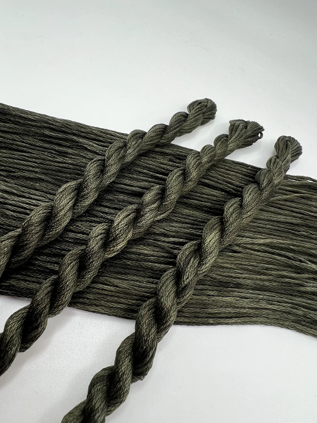Dark green braided embroidery floss  on a white background