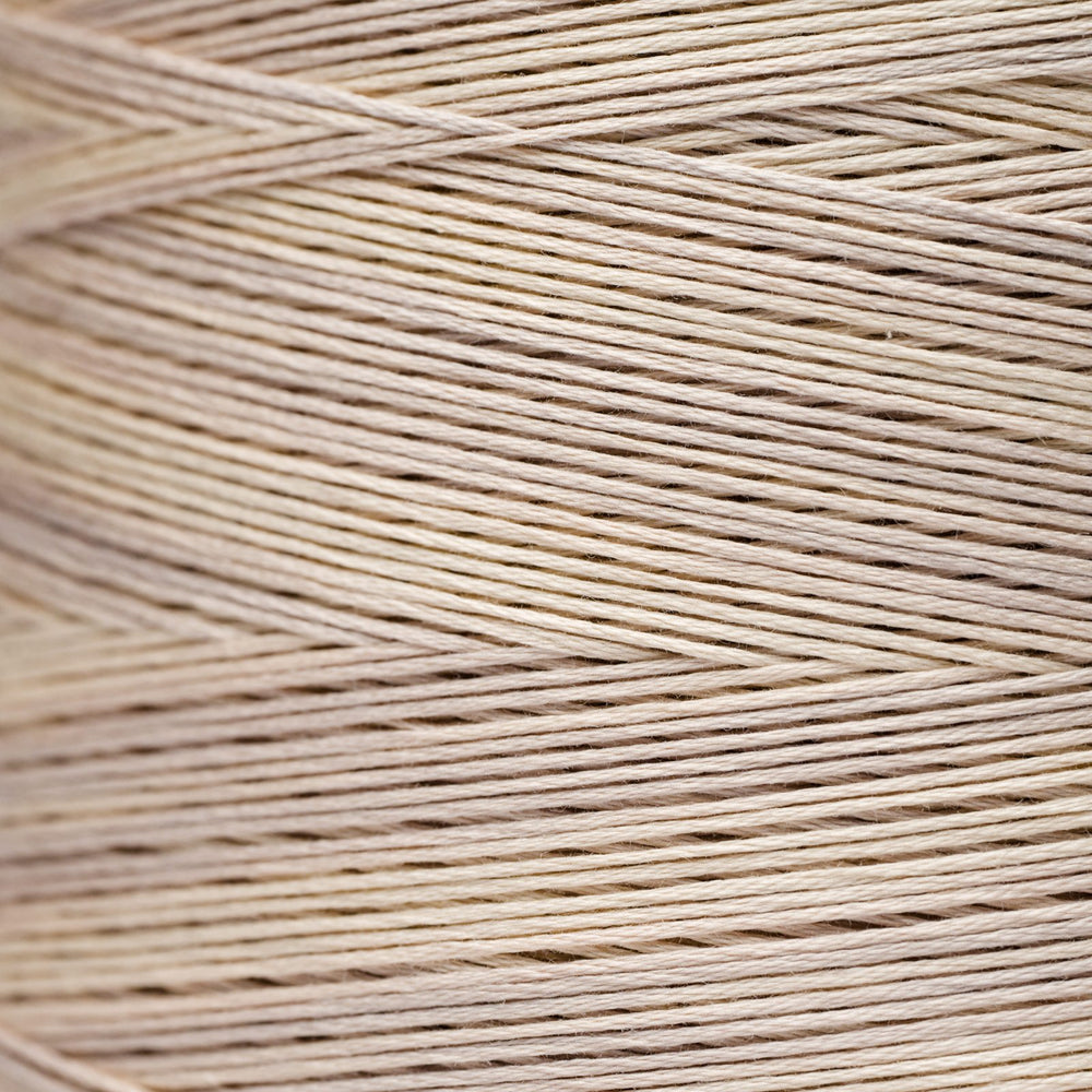 A close-up texture shot of light beige cotton embroidery thread wound in diagonal rows.