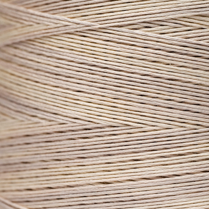 A close-up texture shot of light beige cotton embroidery thread wound in diagonal rows.