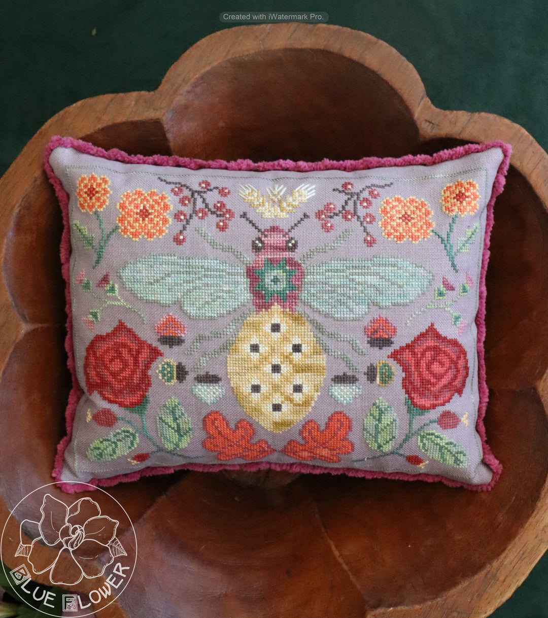 Decorative pillow with floral and butterfly pattern on a wooden surface, featuring the brand 'Blue Flower'.