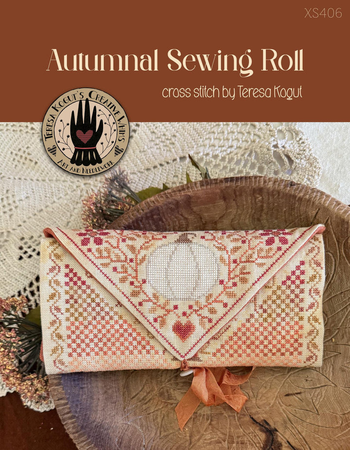 Cross stitch pattern cover for 'Autumnal Sewing Roll' by Teresa Kogut, featuring a finished cross-stitched envelope clutch with a pumpkin and heart design, displayed on a rustic wooden slice with a lace doily.