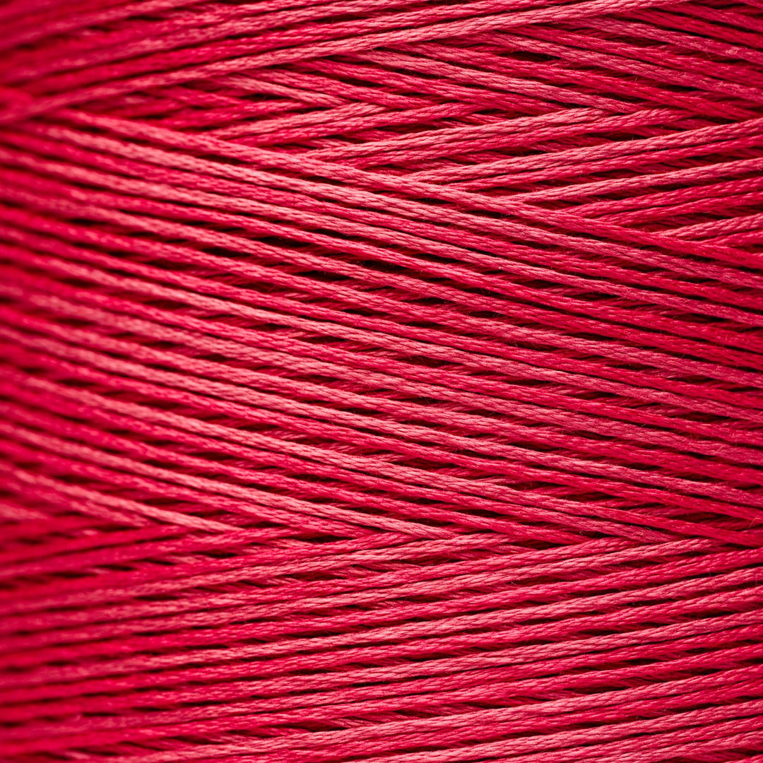 A close-up texture shot of bright pink floss yarn, showing the detailed twisted strands and color.