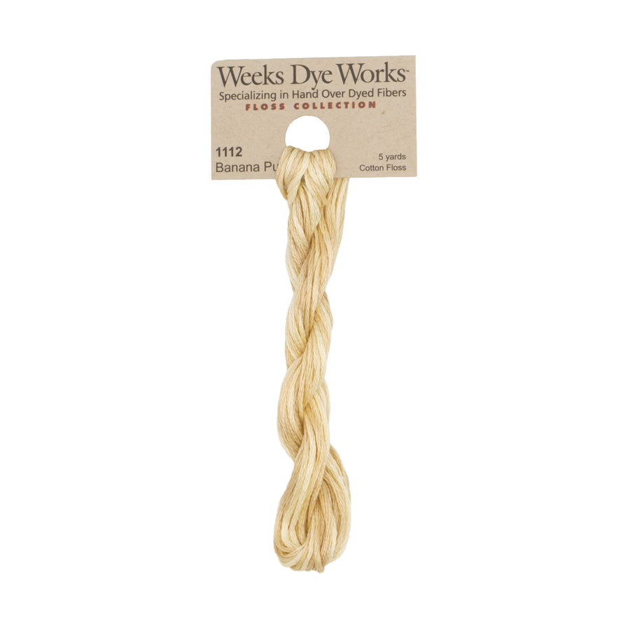 A skein of Weeks Dye Works Banana Pine cotton embroidery floss, showing the light golden-yellow fiber strands hanging from a kraft paper header card.