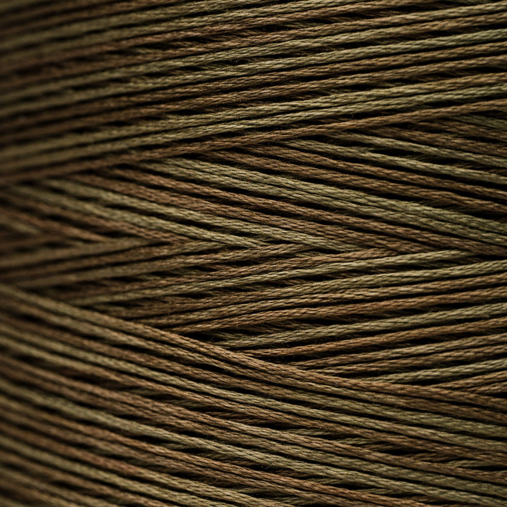 A close-up texture shot of multi-colored braided cord or thread, showing fine strands woven in a diagonal pattern. The color identity is a blend of olive green, brown, and dark brown, creating a muted earthy tone.