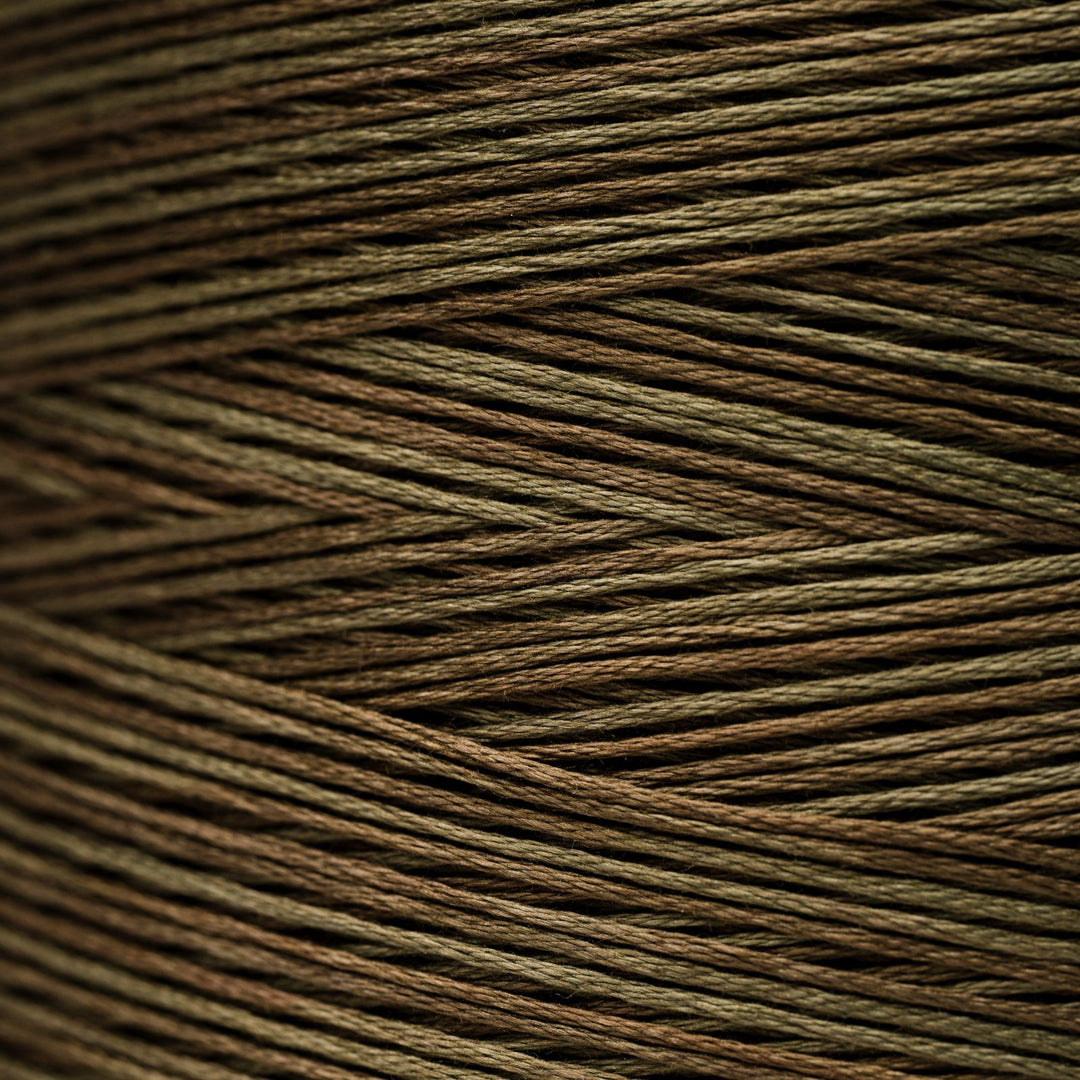 A close-up texture shot of multi-colored braided cord or thread, showing fine strands woven in a diagonal pattern. The color identity is a blend of olive green, brown, and dark brown, creating a muted earthy tone.