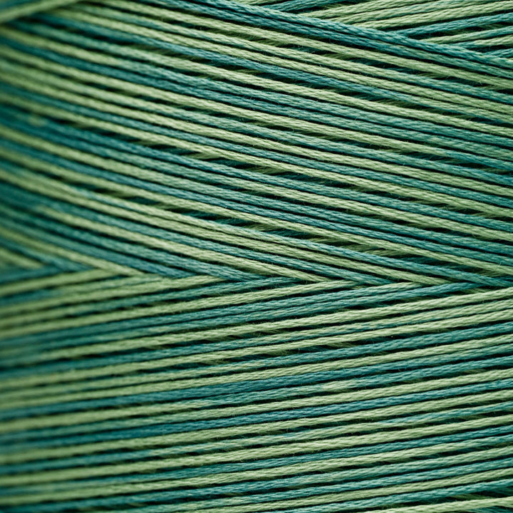 A close-up of tightly wound thread strands in alternating shades of teal blue and light olive green, arranged in a textured chevron pattern.
