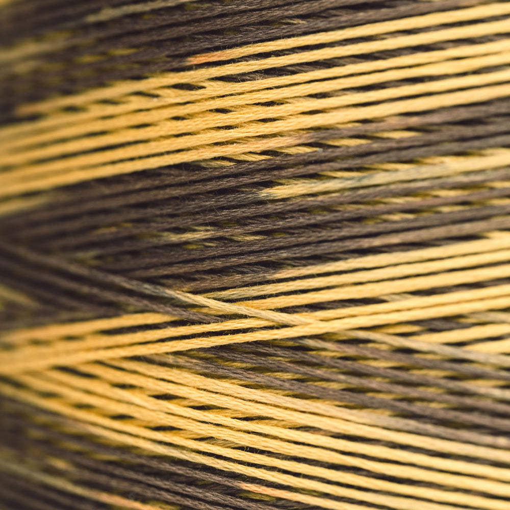 A close-up of wrapped thread of dark brown and warm golden yellow.