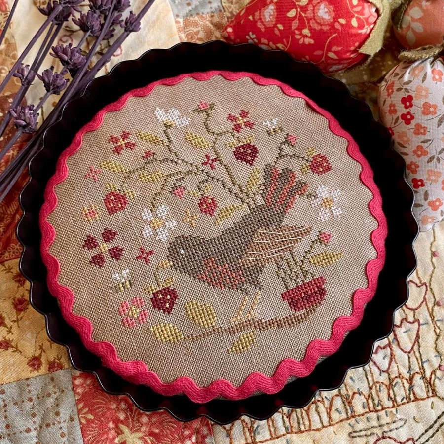 Decorative tart with bird and berry design on a textured surface