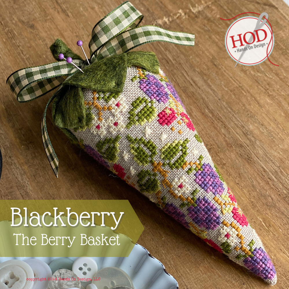 Decorative blackberry-shaped basket with cross-stitch design on a wooden surface, featuring the brand 'HOD'.