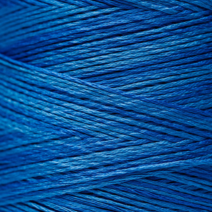 A close-up of tightly wound blue thread strands filling the frame, showing the fiber texture and color variation from deep cobalt blue to brighter royal blue highlights.
