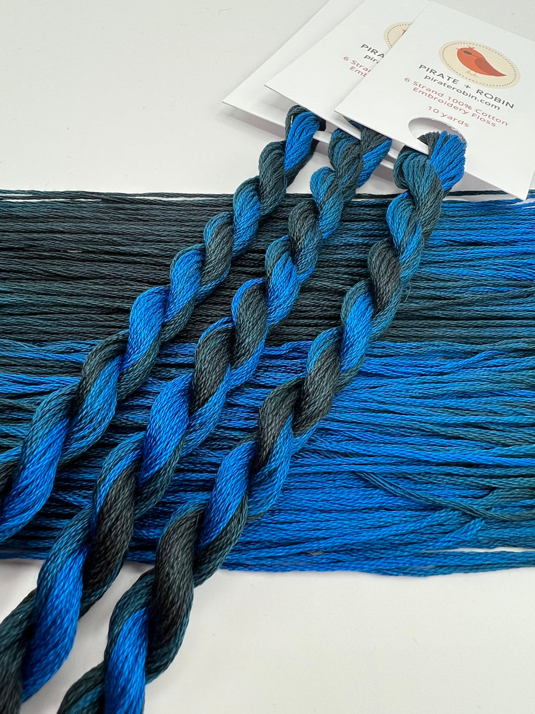 Blue and black braided embroidery floss on a white background