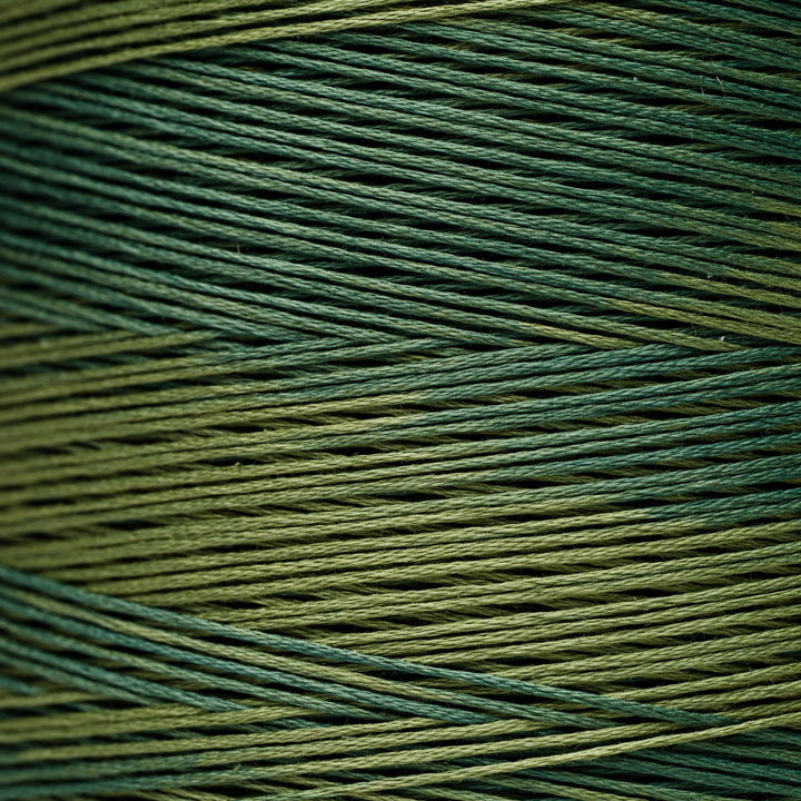 A close-up of tightly wound yarn or thread strands in a variegated colorway of forest green and olive green.