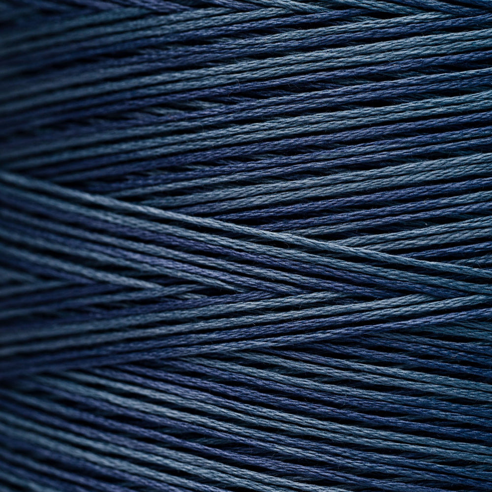 A close-up of tightly wound yarn strands in a deep navy blue color, showing the texture and sheen of the thread.