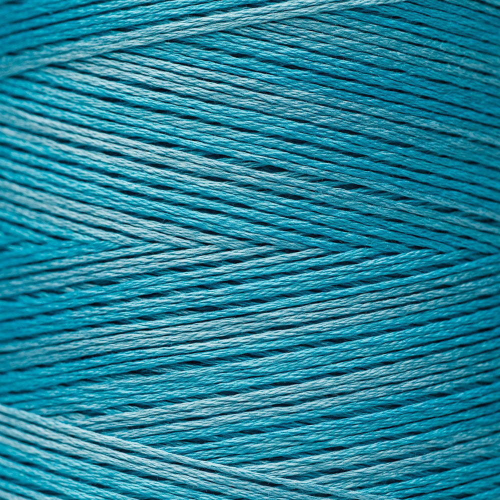 A close-up of tightly wound yarn or thread in a bright teal-blue color, filling the entire frame.