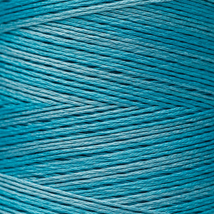 A close-up of tightly wound yarn or thread in a bright teal-blue color, filling the entire frame.