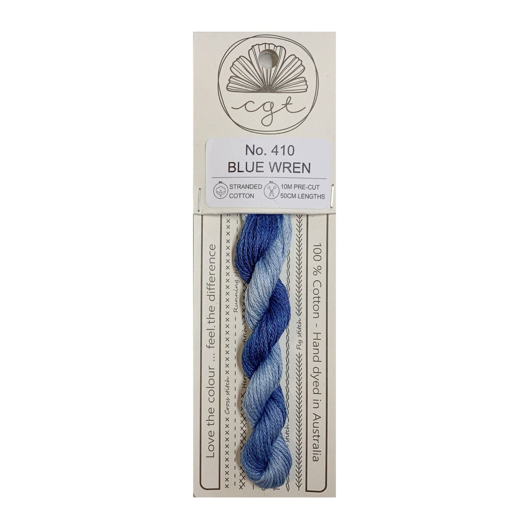 Blue yarn skein on a beige card with branding and product details.