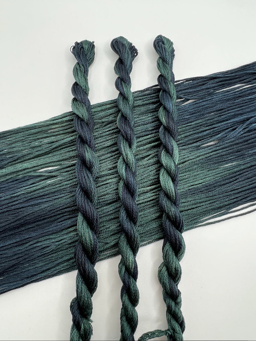 Three braided green skeins on a white background