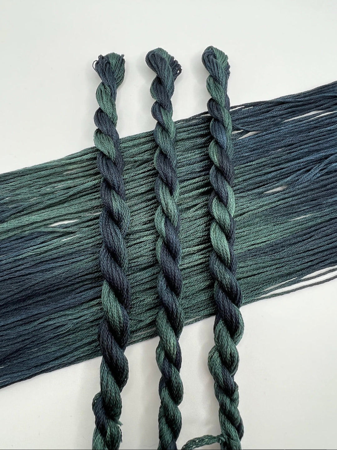 Three braided green skeins on a white background