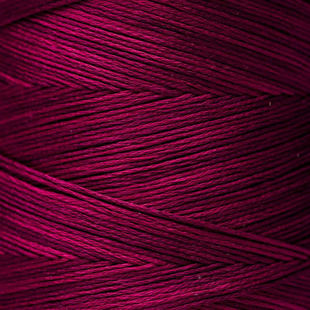 A close-up of tightly wound yarn strands in a rich magenta-purple color, showing the texture and sheen of the fiber.