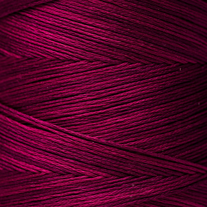 A close-up of tightly wound yarn strands in a rich magenta-purple color, showing the texture and sheen of the fiber.