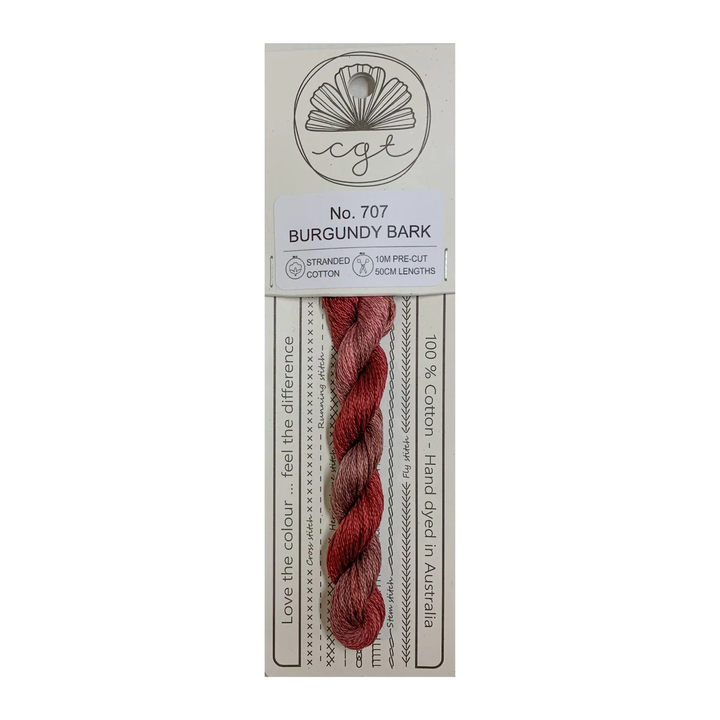Burgundy thread skein on a white background with a label indicating brand and product details.