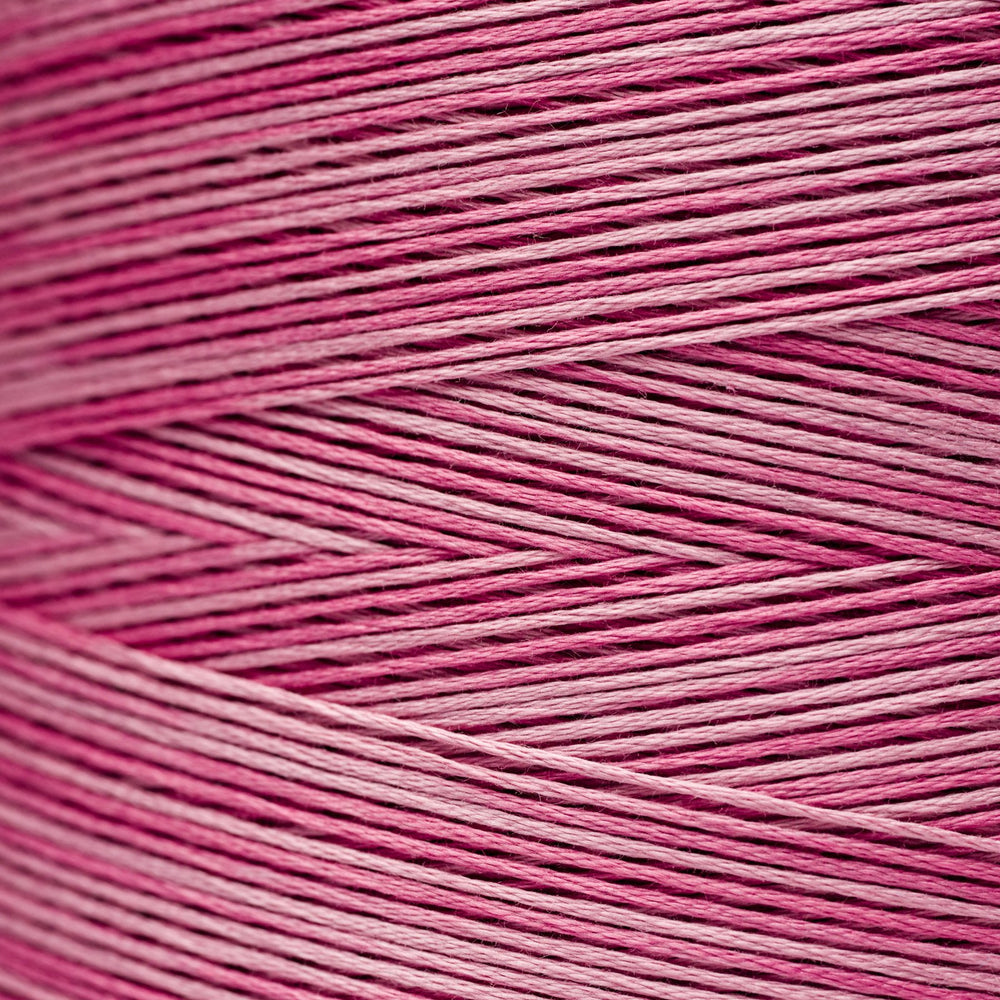A close-up texture shot of pink and magenta embroidery thread wound in diagonal rows.