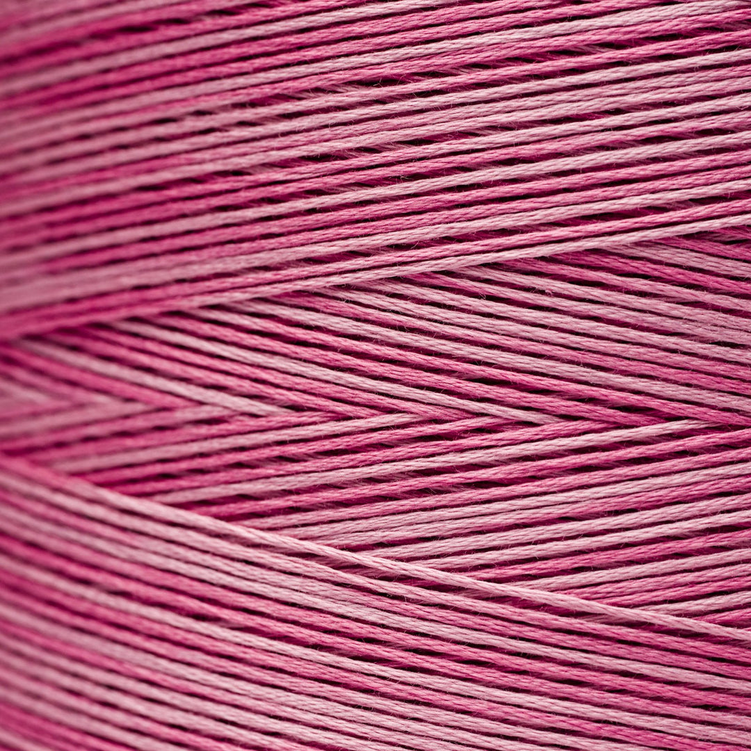 A close-up texture shot of pink and magenta embroidery thread wound in diagonal rows.