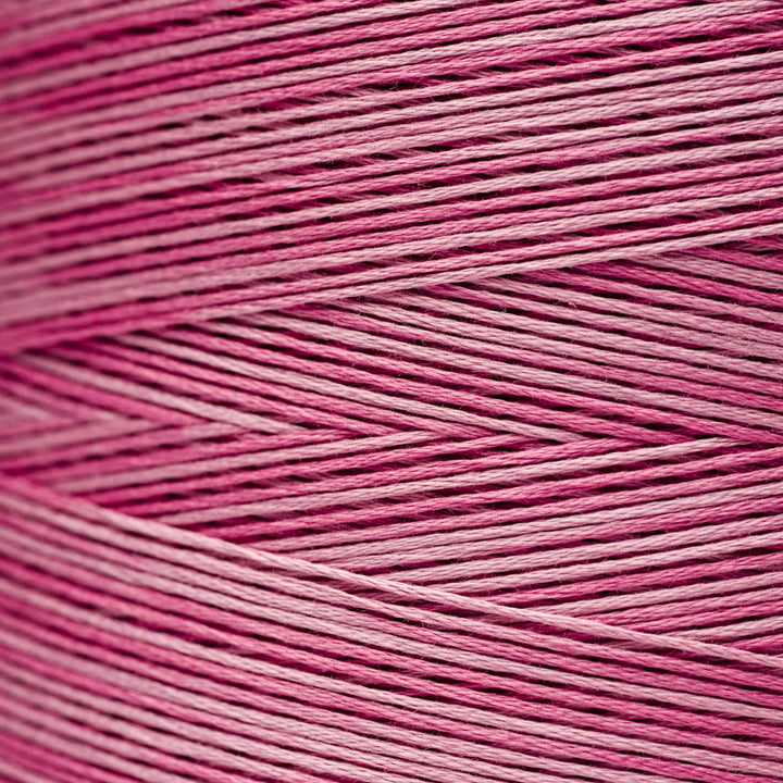 A close-up texture shot of pink and magenta embroidery thread wound in diagonal rows.