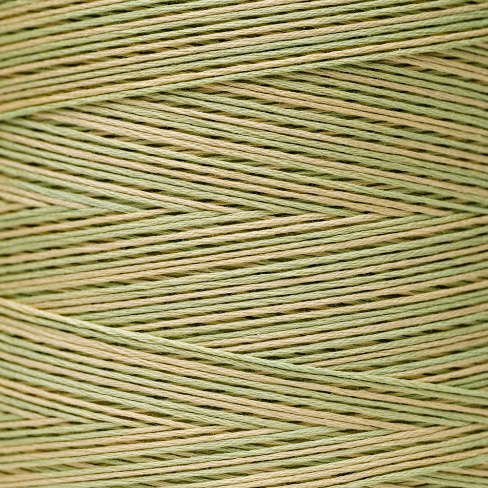 A close-up of tightly wound thread in a two-tone pattern of sage green and light tan, arranged in a herringbone texture.