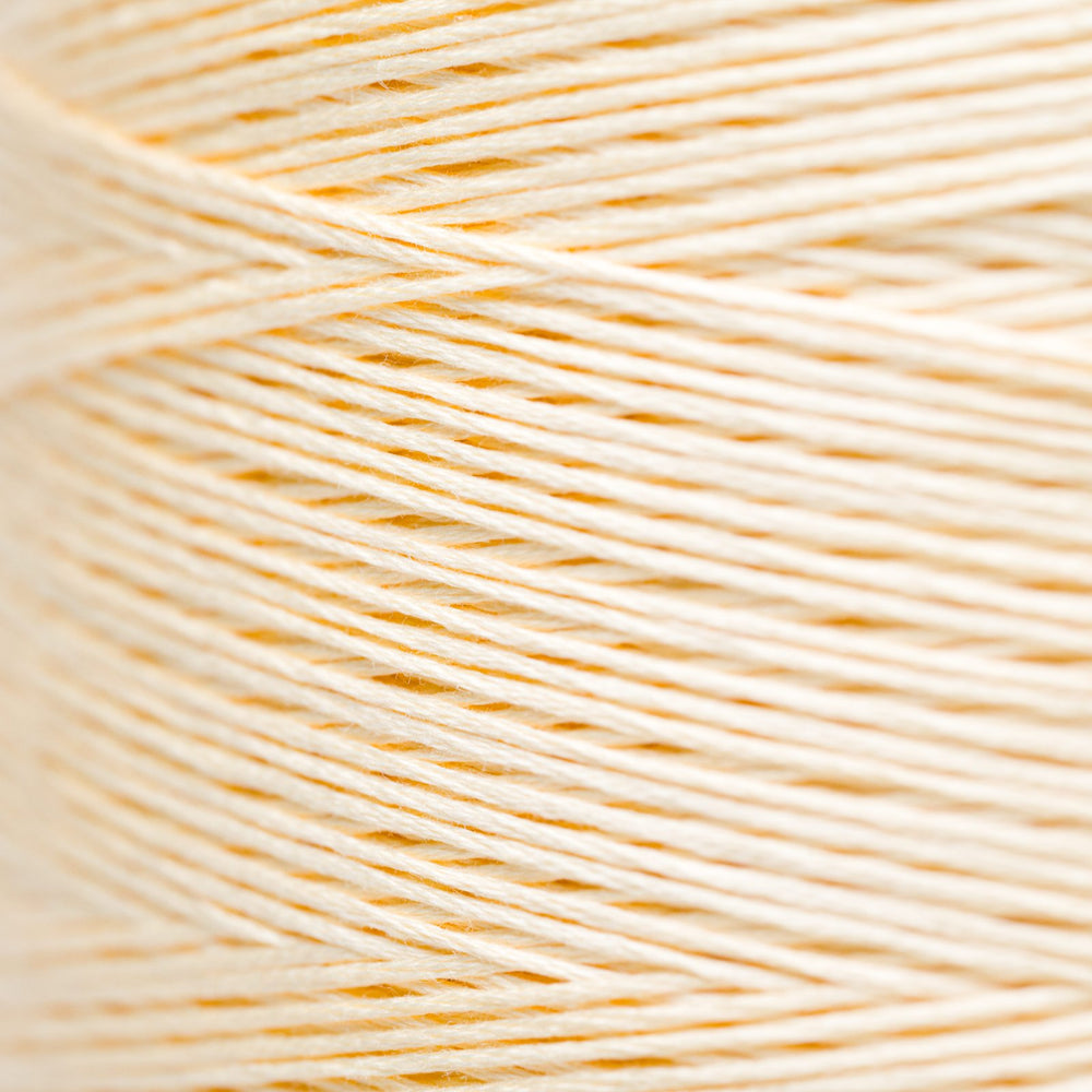 A close-up of cream-colored embroidery thread wound tightly, showing the fine texture of the strands.