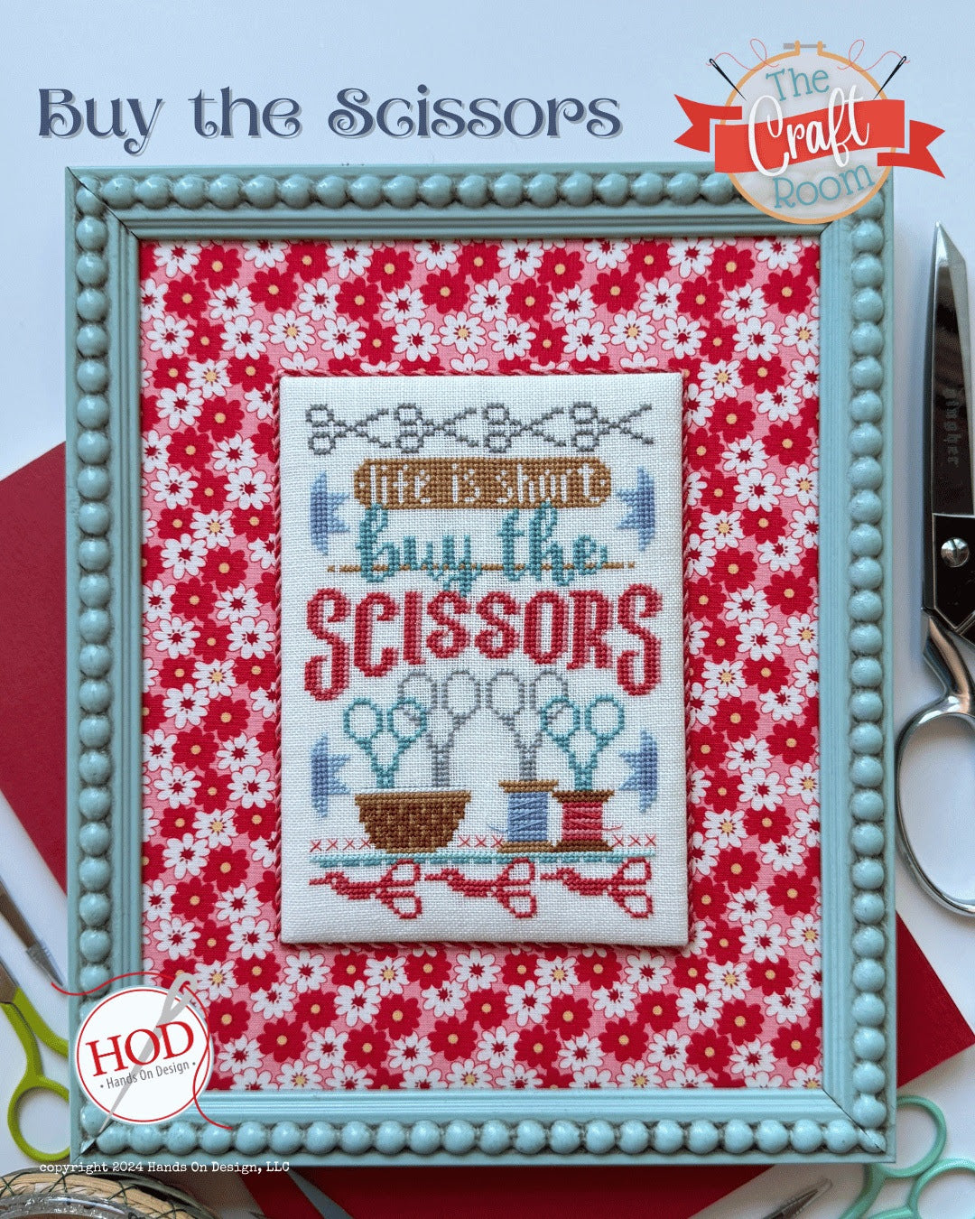 Framed cross-stitched design with 'Buy the Scissors' text on a floral background, with scissors and 'The Craft Room' branding.