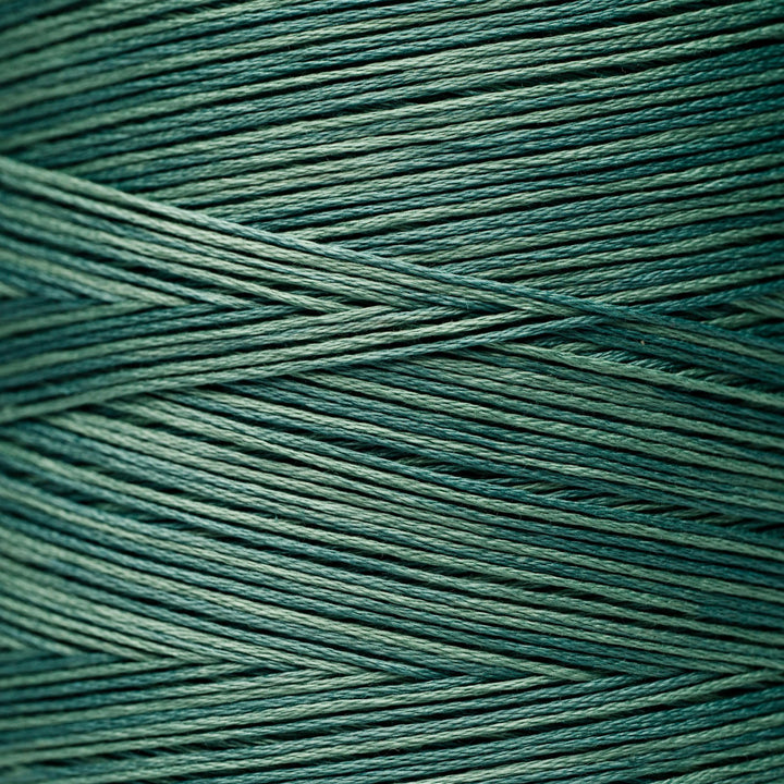 A close-up of tightly wound dark teal-green cord or thread filling the frame, with diagonal strands crossing over each other.