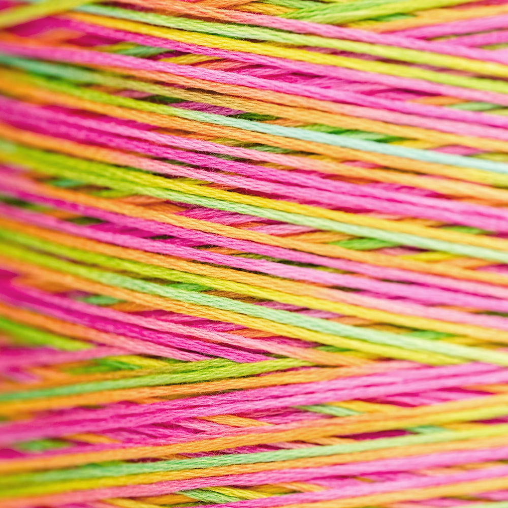 Close-up of multicolored embroidery thread wound tightly, showing bright pink, lime green, yellow, and orange strands crossing diagonally.