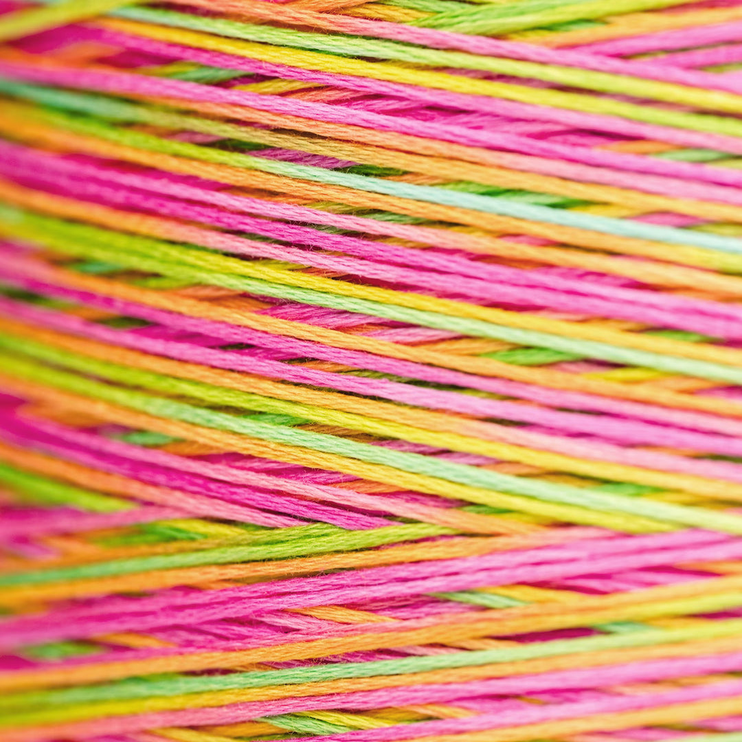 Close-up of multicolored embroidery thread wound tightly, showing bright pink, lime green, yellow, and orange strands crossing diagonally.
