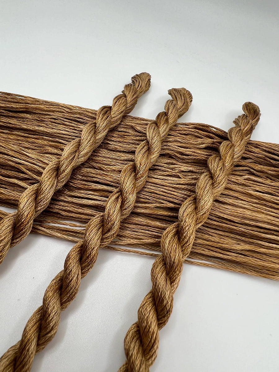 Braided light brown thread on a white background