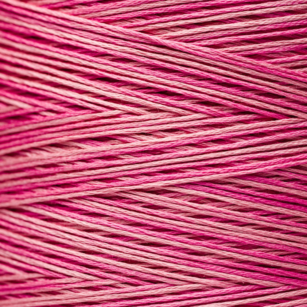 A close-up texture shot of pink and magenta variegated embroidery thread wound in diagonal layers.