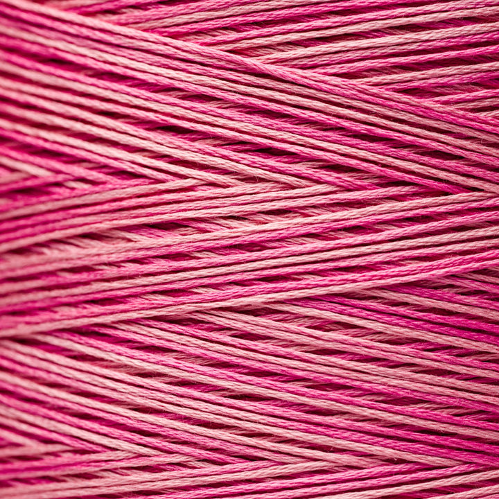 A close-up texture shot of pink and magenta variegated embroidery thread wound in diagonal layers.