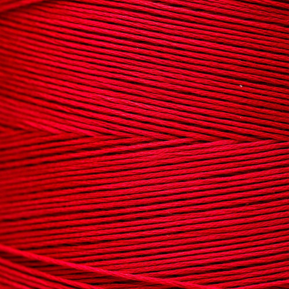 A close-up of bright red yarn or thread wound in horizontal layers, filling the entire frame.