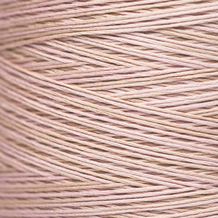 A close-up texture shot of fine yarn wound in a cone, showing the fine strands in a soft dusty pink color.